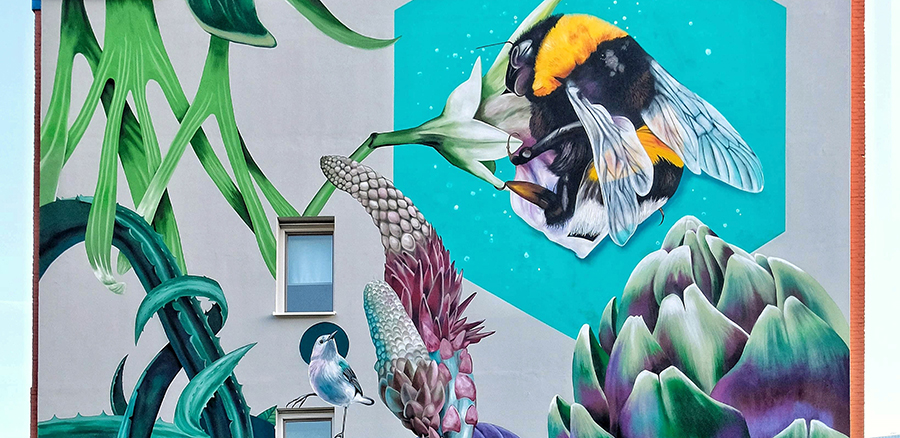 Ett exempel på en Muralmålning som Nina Valkoff har gjort. Här syns en humla, en liten fågel, toppen av en kronärtskocka, växter och grönska.